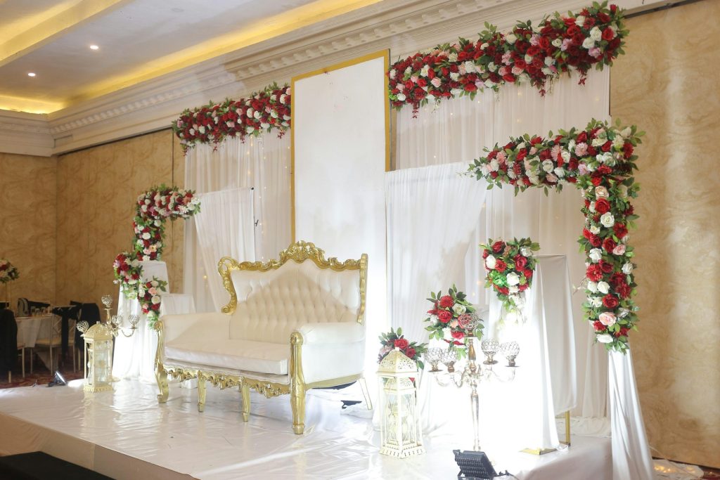 A white tufted sofa with gold trim on a stage decorated with red flowers